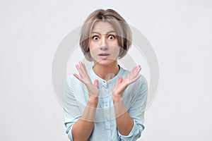 Shocked excited young lady standing isolated over white background.