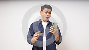 Shocked expression holding credit card and smartphone