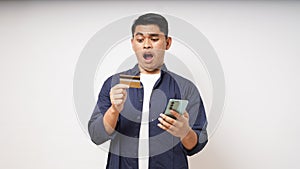 Shocked expression holding credit card and smartphone