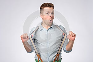 Shocked face of young european man in blue shirt and suspenders