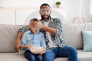 Shocked Father Covering Son& x27;s Eyes Watching Questionable TV Content Indoor
