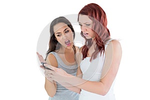 Shocked female friends looking at mobile phone