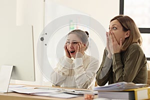 Shocked female managers look at computer monitor at desk