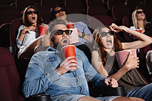 Shocked friends sitting in cinema watch film