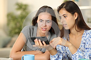 Shocked friends watching media on phone