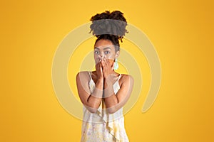 Shocked frightened young black woman in dress covering mouth with hands