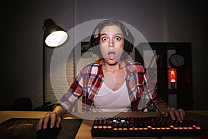 Shocked girl gamer sitting at the table photo