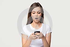 Shocked girl holding phone feeling stunned about unexpected mobile message