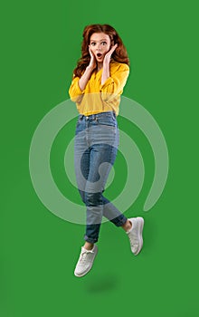 Shocked Girl Jumping Cupping Face In Hands Over Green Background