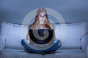 Shocked girl using facebook at night