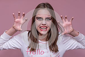 Shocked girl wears frightening makeup, keeps palms raised, scares someone, celebrates Halloween