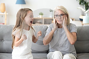 Shocked grandma closing ears not to hear stubborn granddaughter
