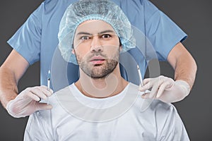 shocked handsome man in medical cap making beauty injections