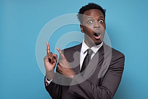 Shocked handsome young black business man pointing his hand up