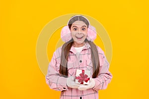 shocked happy kid in winter earmuffs with box. teen girl in mittens hold present