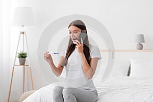 Shocked happy millennial caucasian wife hold pregnancy test and calling to husband with good news