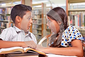 Shocked Hispanic Boy and Girl Studying Together In The Library