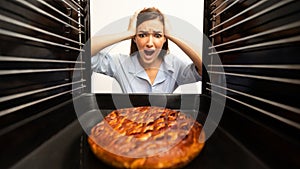 Shocked housewife checking her oven, looking at burnt pie