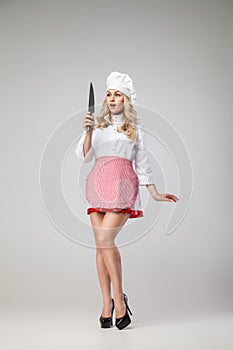 Shocked housewife in uniform looking at knife