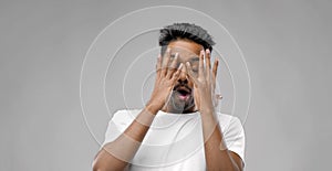 Shocked indian man over grey background