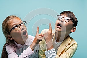 Shocked interracial schoolkids in eyeglasses pointing