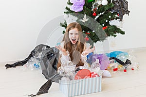 Shocked little child girl looks with opened eyes and worried expression, holding box with various plastic wastes over