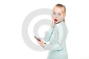 shocked little girl holding smartphone and looking at camera photo