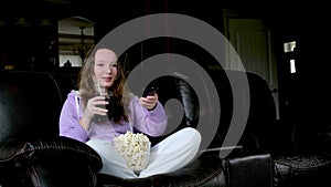 Shocked little teen children girl watching comedy video tv program or movie film content on tv, eating popcorn on