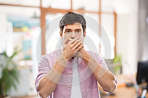 Shocked man closing mouth by hands at office room