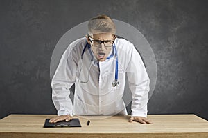 Shocked man doctor surprised by news on laptop