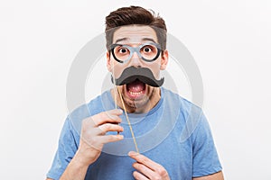 Shocked man in fake mustache and eyeglasses looking at camera