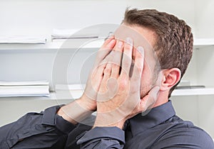 Shocked man hide face at office.