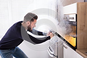 Shocked Man Looking At Burnt Cookies In Oven