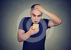 Shocked man looking at his mobile phone seeing bad news reading text message