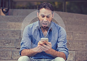 Shocked man looking at mobile phone seeing bad news or reading text message