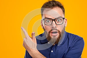 Shocked man pointing away in studio