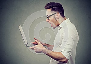 Shocked man reading news on laptop