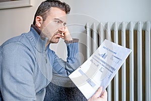 Shocked man reading some utilities bills home heating expenses