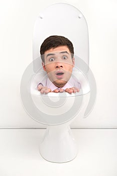 Shocked man sitting inside toilet seat.