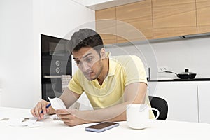 Shocked man sitting and looking at bills at home, Tax and high prices concept