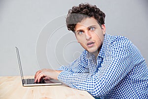 Shocked man sitting at the table with laptop