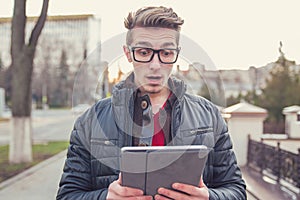 Shocked man watching tablet on street