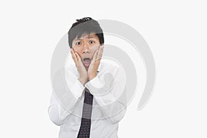 Shocked mid adult businessman with hands on face over white background