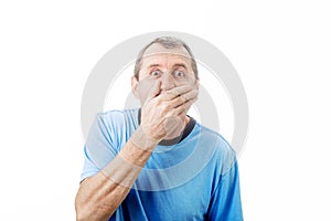 Shocked middle aged man with wide opened eyes covering his mouth with his hand isolated on white background with copy space.