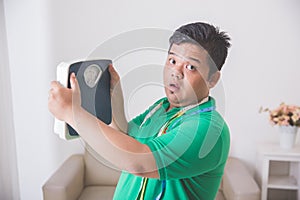 Shocked obese man while looking at a weight scale