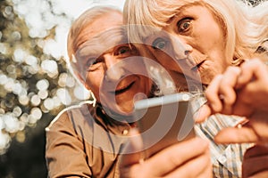 Shocked old woman and smiling man using smartphone