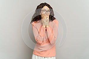 Shocked positive girl smile cover mouth with hand, giggle. Excited surprised young woman portrait