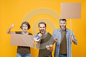 Shocked protesting young people guys girl hold protest signs broadsheet blank placard on stick scream in megaphone photo