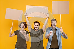 Shocked protesting young three people hold protest signs broadsheet blank placard on stick point on camera screaming photo