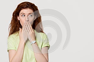 Shocked redhead woman cover mouth with hands looking at copyspace